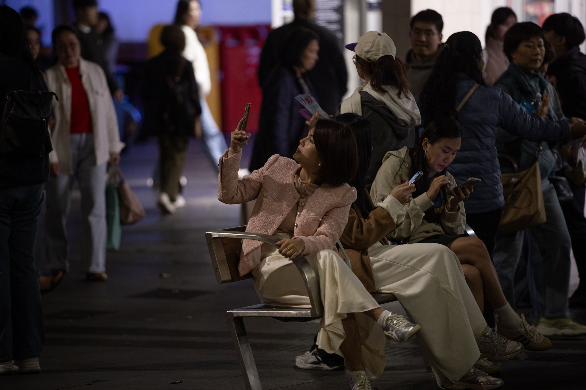 A lone seagull guides the steps in front of Sydney Town Hall, the interior barely visible through the frosted glass and casting a warm, inviting glow despite the closed doors. Thick stone columns are paired either side of the door, two pairs of two columns either side supporting the substantial roof.
Tarnished light grey stone steps lead down from the doors down to street level, where a couple clad in white clothing are looking down at a phone held in the man's hand, a slight smile visible from them both.